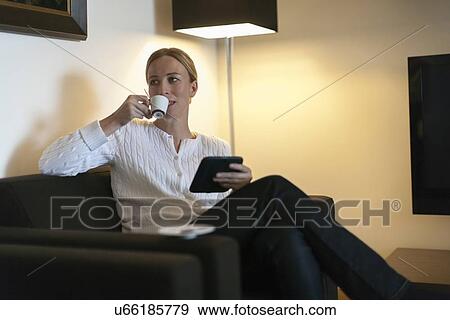 Woman using digital tablet and drinking coffee at home View Large Photo Image Stock Photo - Woman using digital tablet and drinking coffee at home. Fotosearch