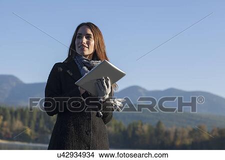 Woman with tablet by lake View Large Photo Image Picture - Woman with tablet by lake. Fotosearch