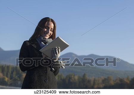 Stock Photo - Woman with tablet by lake. Fotosearch