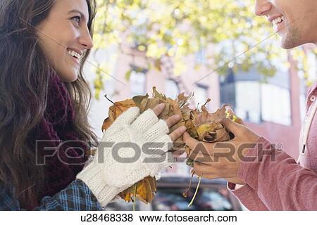 Young couple holding autumn leaves View Large Photo Image Stock Photo - Young couple holding autumn leaves. Fotosearch