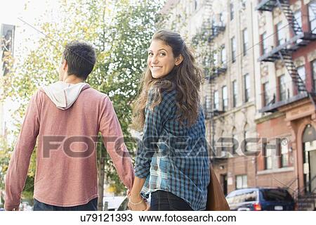 Young couple holding hands on sidewalk View Large Photo Image Stock Image - Young couple holding hands on sidewalk. Fotosearch