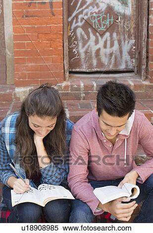 Stock Photography - Young couple reading book and doing crossword. Fotosearch