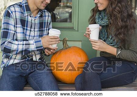 Young couple sitting on bench with coffee cups View Large Photo Image Stock Photo - Young couple sitting on bench with coffee cups. Fotosearch