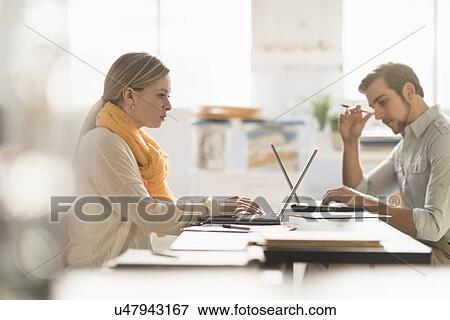 Young man and woman working at desk in office View Large Photo Image Stock Photo - Young man and woman working at desk in office. Fotosearch
