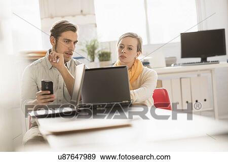 Young man and woman working together with laptop in office View Large Photo Image Stock Photo - Young man and woman working together with laptop in office. Fotosearch