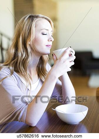 Young woman drinking coffee at table View Large Photo Image Stock Photograph - Young woman drinking coffee at table. Fotosearch