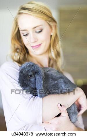 Young woman holding bunny View Large Photo Image Stock Photo - Young woman holding bunny. Fotosearch