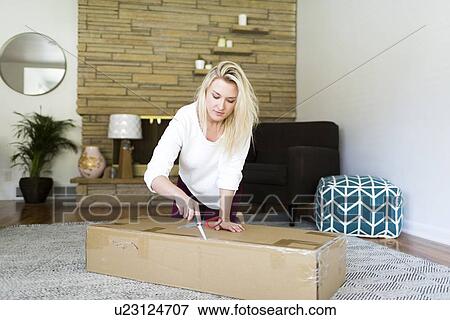 Young woman opening box with scissors View Large Photo Image Stock Photo - Young woman opening box with scissors. Fotosearch