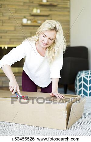 Young woman opening box with scissors View Large Photo Image Stock Photograph - Young woman opening box with scissors. Fotosearch