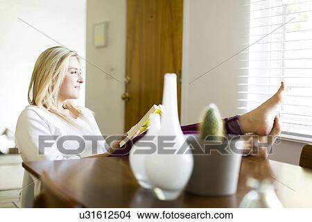 Young woman reading book at table View Large Photo Image Picture - Young woman reading book at table. Fotosearch