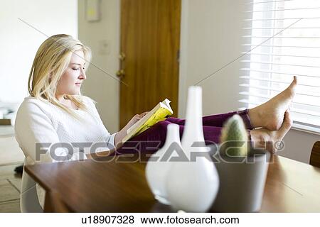 Young woman reading book at table View Large Photo Image Stock Photo - Young woman reading book at table. Fotosearch