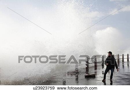 Stock Photo - Man on sea front with crashing waves. Fotosearch