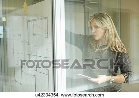 Architect looking at plans taped to glass wall View Large Photo Image Picture - Architect looking at plans taped to glass wall. Fotosearch