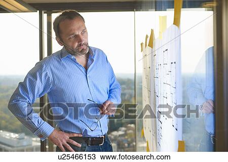 Architect looking at plans taped to glass wall View Large Photo Image Stock Image - Architect looking at plans taped to glass wall. Fotosearch