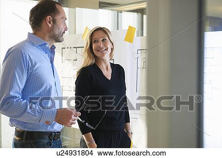 Architects standing by plans on glass wall View Large Photo Image Picture - Architects standing by plans on glass wall. Fotosearch