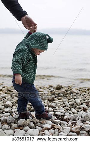"Baby girl holding fathers hand stepping on lakeside pebbles, Lake Starnberg, Bavaria, Germany" View Large Photo Image Stock Photo - "Baby girl holding fathers hand stepping on lakeside pebbles, Lake Starnberg, Bavaria, Germany". Fotosearch