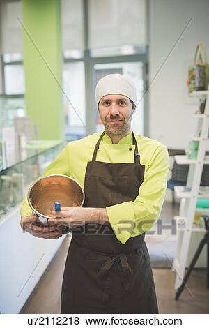 Stock Photo - Baker carrying mixing bowl in cafe. Fotosearch