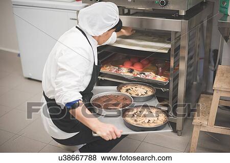 Baker placing cakes into warmer View Large Photo Image Stock Photo - Baker placing cakes into warmer. Fotosearch