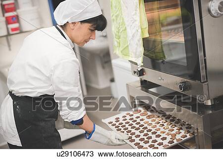 Baker placing tray of star-shaped cookies into oven View Large Photo Image Stock Image - Baker placing tray of star-shaped cookies into oven. Fotosearch