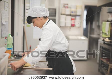 Stock Photo - Baker rolling dough in kitchen. Fotosearch