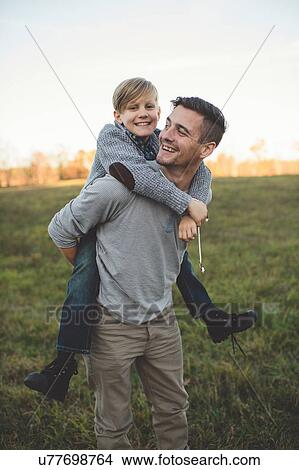 Picture - Boy getting piggy back from father in field. Fotosearch