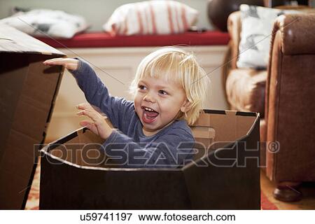 Boy hiding in cardboard box in living room View Large Photo Image Stock Photo - Boy hiding in cardboard box in living room. Fotosearch