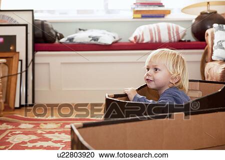 Boy playing in cardboard box in living room View Large Photo Image Stock Image - Boy playing in cardboard box in living room. Fotosearch
