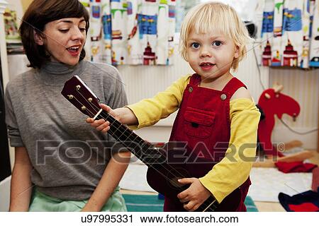 Stock Image - Boy playing toy guitar for mother. Fotosearch