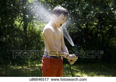 Stock Photo - Boy playing with garden hose. Fotosearch