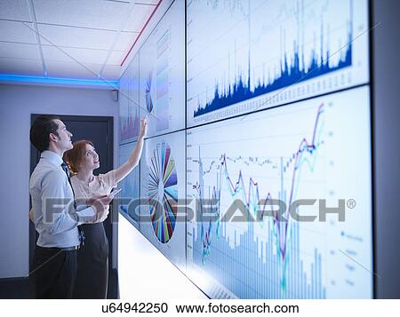 Business colleagues studying graphs on screen in meeting room View Large Photo Image Stock Image - Business colleagues studying graphs on screen in meeting room. Fotosearch