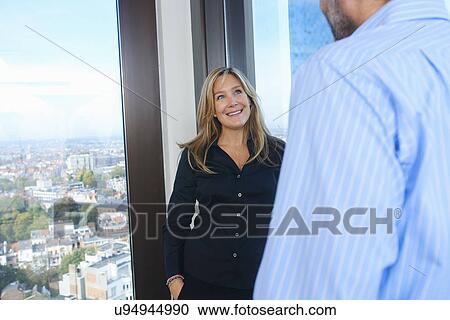 "Businessman and woman chatting in skyscraper office, Brussels, Belgium" View Large Photo Image Stock Image - "Businessman and woman chatting in skyscraper office, Brussels, Belgium". Fotosearch
