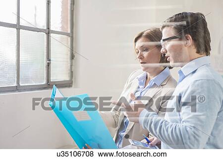Businessman and woman reading file in office View Large Photo Image Stock Photo - Businessman and woman reading file in office. Fotosearch
