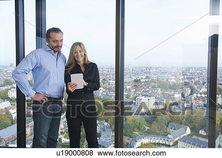 "Businessman and woman using digital tablet in front of office window with Brussels cityscape, Belgium" View Large Photo Image Stock Photo - "Businessman and woman using digital tablet in front of office window with Brussels cityscape, Belgium". Fotosearch