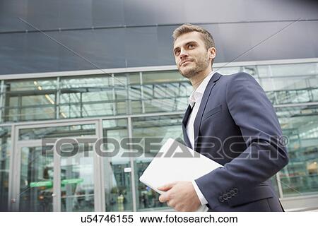 Stock Photography - Businessman carrying digital tablet at airport. Fotosearch