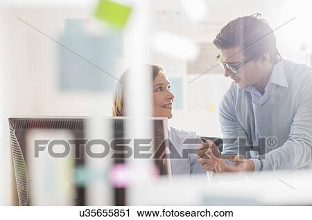 Businessman explaining to female colleague in office View Large Photo Image Stock Image - Businessman explaining to female colleague in office. Fotosearch