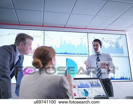 Businessman making presentation to colleagues in front of graphs on screen View Large Photo Image Stock Image - Businessman making presentation to colleagues in front of graphs on screen. Fotosearch