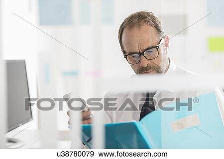 Businessman reading paperwork and using smartphone View Large Photo Image Stock Photo - Businessman reading paperwork and using smartphone. Fotosearch
