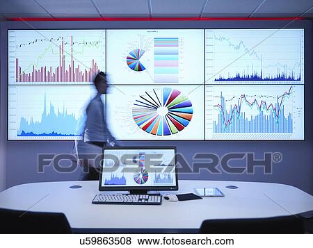 Stock Photo - Businessman walking in front of graphs on screen. Fotosearch