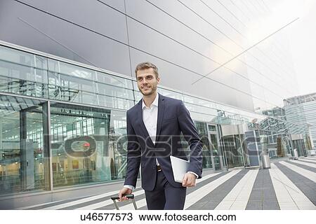 Businessman with wheeled suitcase and digital tablet at airport View Large Photo Image Stock Image - Businessman with wheeled suitcase and digital tablet at airport. Fotosearch