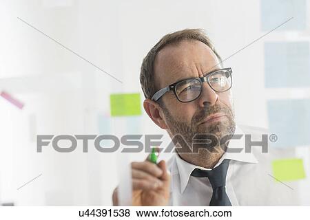 Businessman writing ideas on adhesive notes for glass wall View Large Photo Image Stock Photo - Businessman writing ideas on adhesive notes for glass wall. Fotosearch