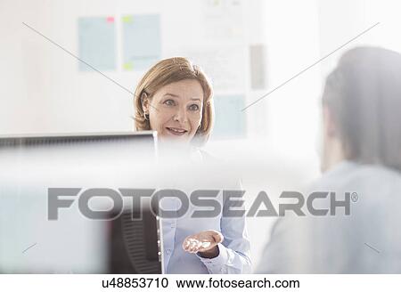 Businesswoman explaining to male colleague in office View Large Photo Image Stock Image - Businesswoman explaining to male colleague in office. Fotosearch