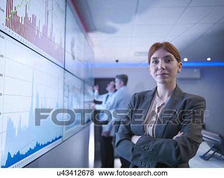 Stock Photo - "Businesswoman in front of graphs on screen in meeting room, portrait". Fotosearch