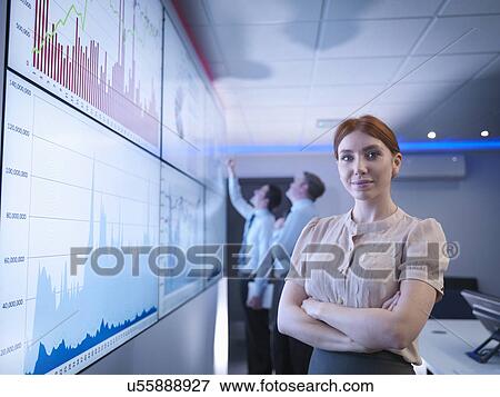 Stock Photo - "Businesswoman in front of graphs on screen in meeting room, portrait". Fotosearch