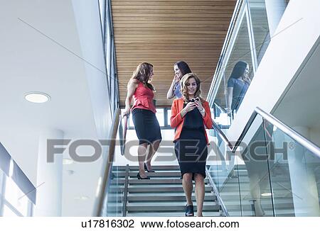 Businesswoman moving down office stairway reading smartphone text View Large Photo Image Stock Image - Businesswoman moving down office stairway reading smartphone text. Fotosearch