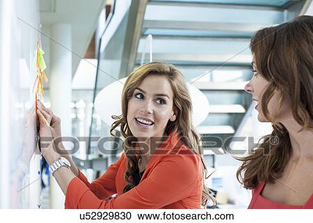 Stock Image - Businesswoman presenting ideas on office whiteboard. Fotosearch