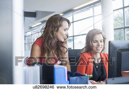 Stock Photograph - Businesswoman presenting ideas to team at office desk. Fotosearch