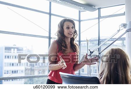 Businesswoman presenting to team at office desk View Large Photo Image Stock Photo - Businesswoman presenting to team at office desk. Fotosearch