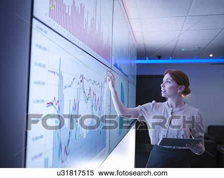 Stock Photography - Businesswoman studying graphs on screens. Fotosearch