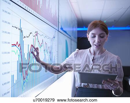 Stock Photo - Businesswoman studying graphs on screens with digital tablet. Fotosearch