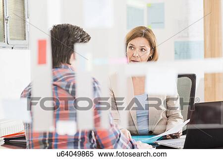 Businesswoman talking to businessman at office desk View Large Photo Image Stock Photography - Businesswoman talking to businessman at office desk. Fotosearch